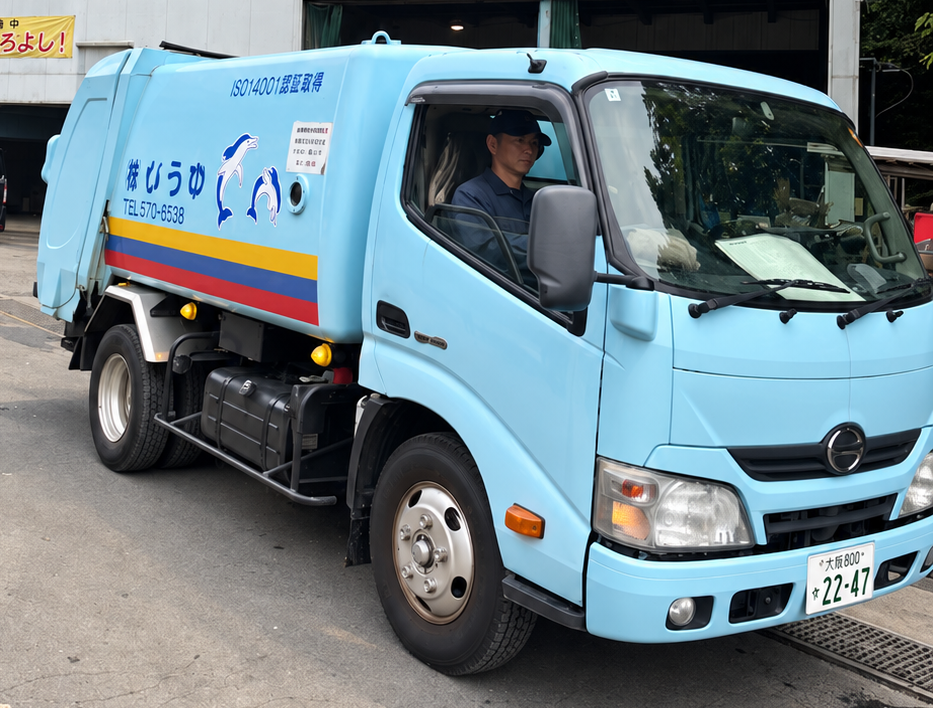 会社の建物の前に停まる、運転席にスタッフが乗ったゆうびの収集車両。